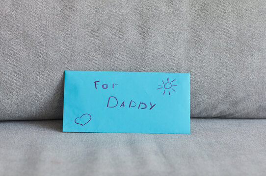 Minimal background image of blue envelope for daddy with letter and handmade gift on Fathers day, copy space