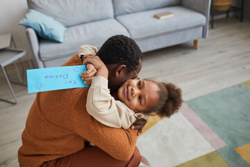 Portrait of happy father embracing little girl after coming home from work on Fathers day, copy space
