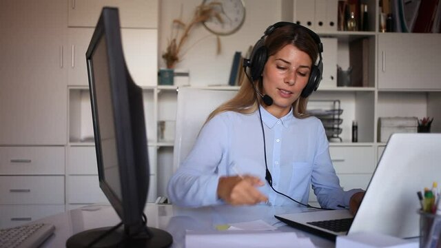 positive woman working with headphones on her laptop in white room