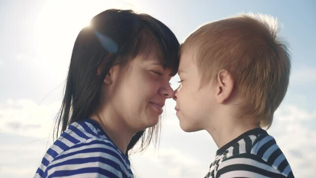 son and mom cute video concert mother's lifestyle day. teamwork happy family boy kisses mother on the cheek touches his nose. parent takes care of the child. kid and adult woman mom in the sunlight at