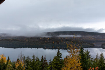 Vue d'une rive d'un lac calme avec nuages très bas en automne 