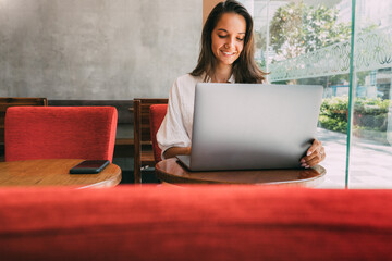 Young pretty girl works for her laptop while sitting in a cafe. Business lady not in office