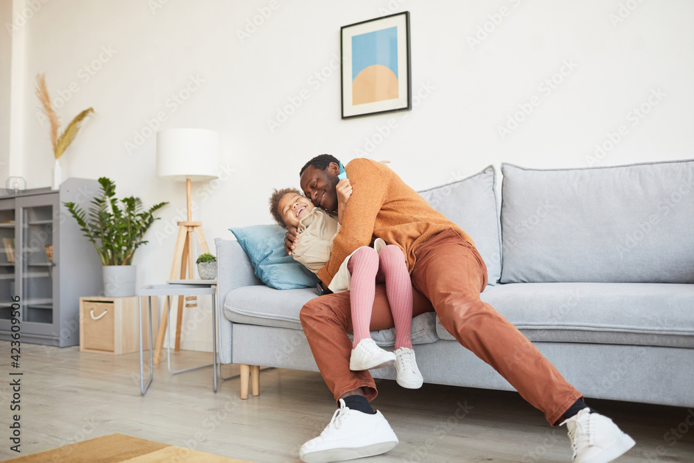 Wall mural full length portrait of happy african-american father embracing daughter after coming home from work