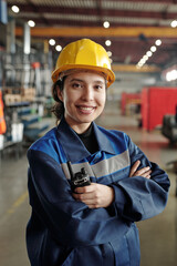 Young successful female worker of modern industrial plant in workwear and protective helmet...