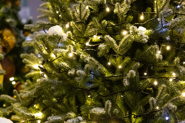 fresh christmas tree covered with snow and decorated with garland festive decor