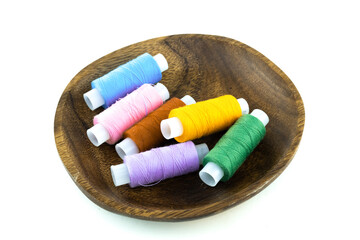 assorted needlework threads folded in a wooden bowl on an isolated background
