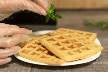 Viennese waffles with banana and mint leaf. Delicate homemade Belgian waffles on a white plate in the kitchen.