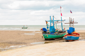 Fototapeta na wymiar pair of fishing boats stand on a shallow against the low tide of the ocean with copy space