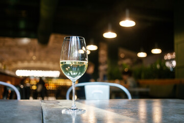 Glass of white wine in restaurant setting.