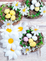 Spotted Easter eggs in bird nests on a wooden background.