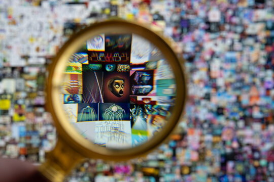 Magnifying glass in front of ipad screen with Beeple digital art EVERYDAYS: THE FIRST 5000 DAYS. Collage art signed with non fungible token. Concept. Stafford, United Kingdom, March 28, 2021.