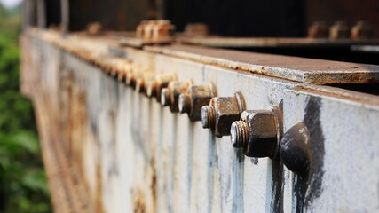 Rusted nuts and bolts on the old bridge. On the gray steel beam there are many anchor bolts which are part of the truss bridge with a copy area. Close focus and object selection