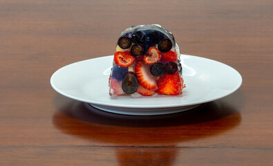 Slice of red fruit gelatin on the wooden table in white dish in closeup