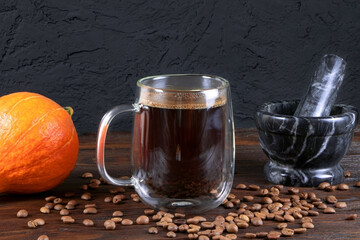 A cup of coffee on wooden table. A glass mug of coffee. Pumpkin on a wooden background. Morning coffee