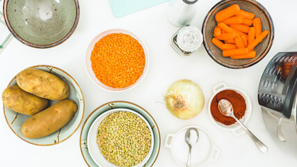 Lentil soup ingredients.  Red lentils, green lentils, onion, carrot, potatoes, and some seasoning close up on white background.