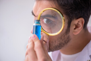 Young male chemist doctor holding vial