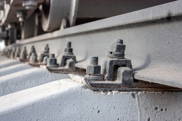 Bolted rail fastening to reinforced concrete sleepers. Connecting the rails with sleepers. Fragment of railway tracks, close-up.