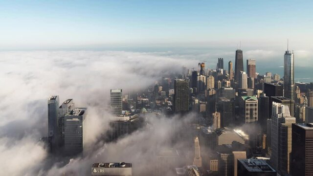 Aerial skyline urban time lapse of heavy fog flowing towards downtown Chicago and engulfing buildings before dissipating into the air as the weather begins to warm up.