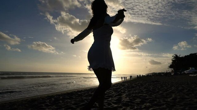 Excited woman dancing on the beach during sunset, super slow motion