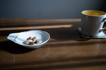 白い皿の上に置かれたアーモンドやカシューナッツとその近くに置かれたマグカップ