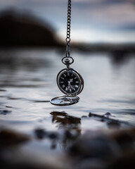 pocket watch hanging above a lake photography
