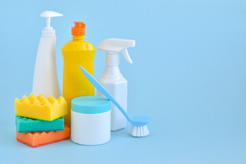 Cleaning products and sponges on light blue. Bottles of detergent and water. The concept of cleaning in the house, apartment, office. Household chemicals. Spring.