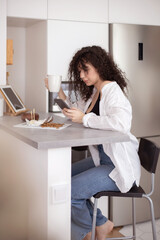 Obraz na płótnie Canvas Joyful brunette woman chatting surfing internet use smartphone enjoying coffee break at cafe