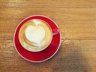 Coffee, a cup of cappuccino with latte art on wooden background. Red ceramic cups top view closeup, place for text