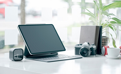 Creative studio with blank screen tablet, camera and gadget on white top table.
