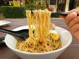 Close up food macro ramen noodles with chopsticks on greenery outdoor background