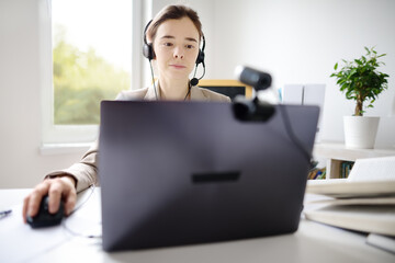 Young woman is learning language with laptop computer, camcorder and headphone online at home....