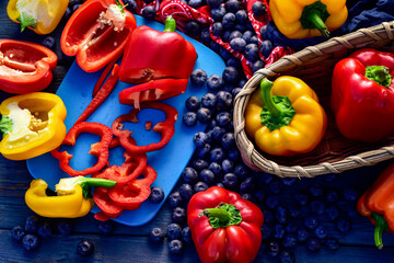 tabletop food preparation with fresh blueberries sweet and savory red and yellow bell peppers