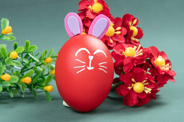 red egg with easter rabbit drawn on yellow straw background