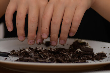 Hands stained with pieces of cookies to prepare easter egg