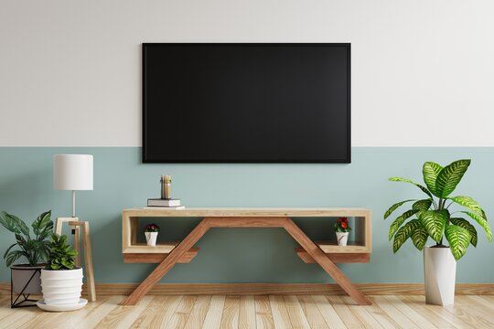TV on the green-white wall in the living room is decorated with a TV cabinet with a lamp and plant pots on the wooden floor.3d rendering.