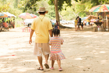 A father takes his child for a walk in the nature market, an Asian family.