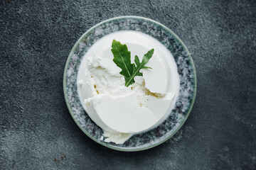 homemade riccota cheese is delicious and fresh with herbs on plate on dark gray background. traditional Italian whey cheese. cooking at home. top view, selective focus