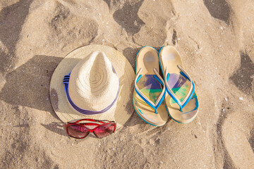 BEACH PARAPHERNALIA ON THE SAND: SUNGLASSES, SANDALS, HAT. TRAVEL TO THE SEA