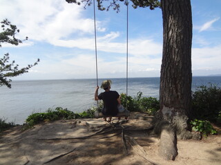 father and child on a beach swing