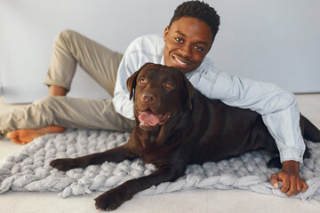 Handsome black man sitting on a blue background with a dog
