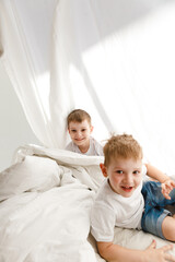 Obraz premium Indoor positive activity. Small children playing on a bed and having fun in sheet hut