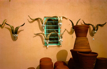 Antelope skulls and horns adorning an adobe wall with pottery in the foreground. Santa Fe, New Mexico, 1993