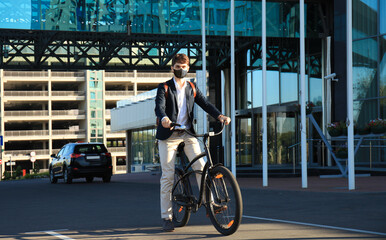 Obraz premium Handsome man in protective mask riding a bicycle to find job.
