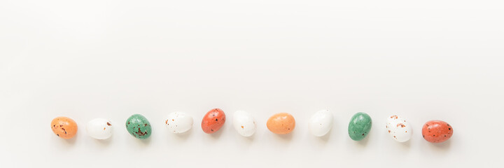 Easter minimal composition with multicolored eggs on the white background. Easter concept. Copy space, flat lay. Banner.