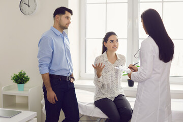 Gynecology consultation. Worried woman and her husband tell a female doctor at a fertility clinic...
