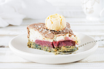 A broken piece of cake on a saucer, close-up, without eggs and gluten, with a creamy strawberry layer, on a light wooden background.