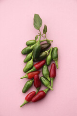 Green and red chili peppers are laid out as peppers on a pink background