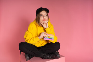 Girl sits on a pink cube and holds a card with the words love is love and lgbt heart