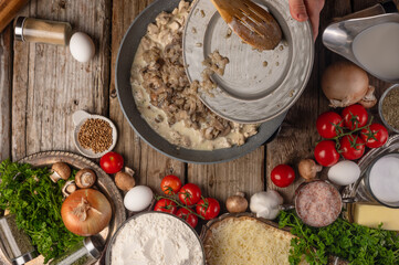 Chef prepares frying mushrooms with meat, top view on the background of ingredients, culinary recipes