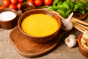 Bowl with tasty garlic cream soup on wooden background